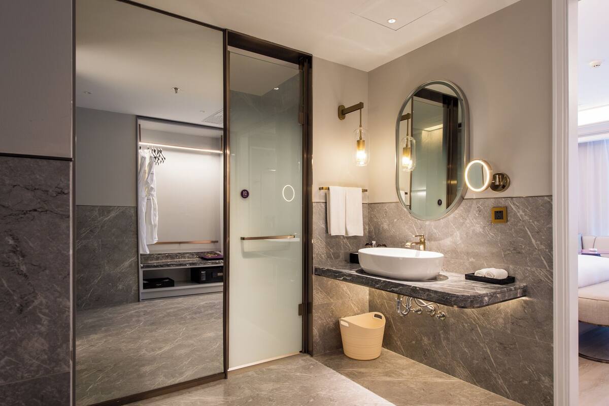 A modern bathroom with a glass-enclosed shower, a vanity with a sink, and a large mirror.