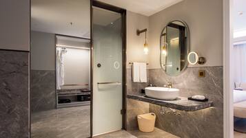 A modern bathroom with a glass-enclosed shower, a vanity with a sink, and a large mirror.