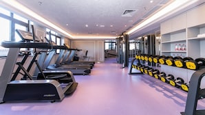 Un gimnasio con cintas de correr, elípticas y un estante de mancuernas.