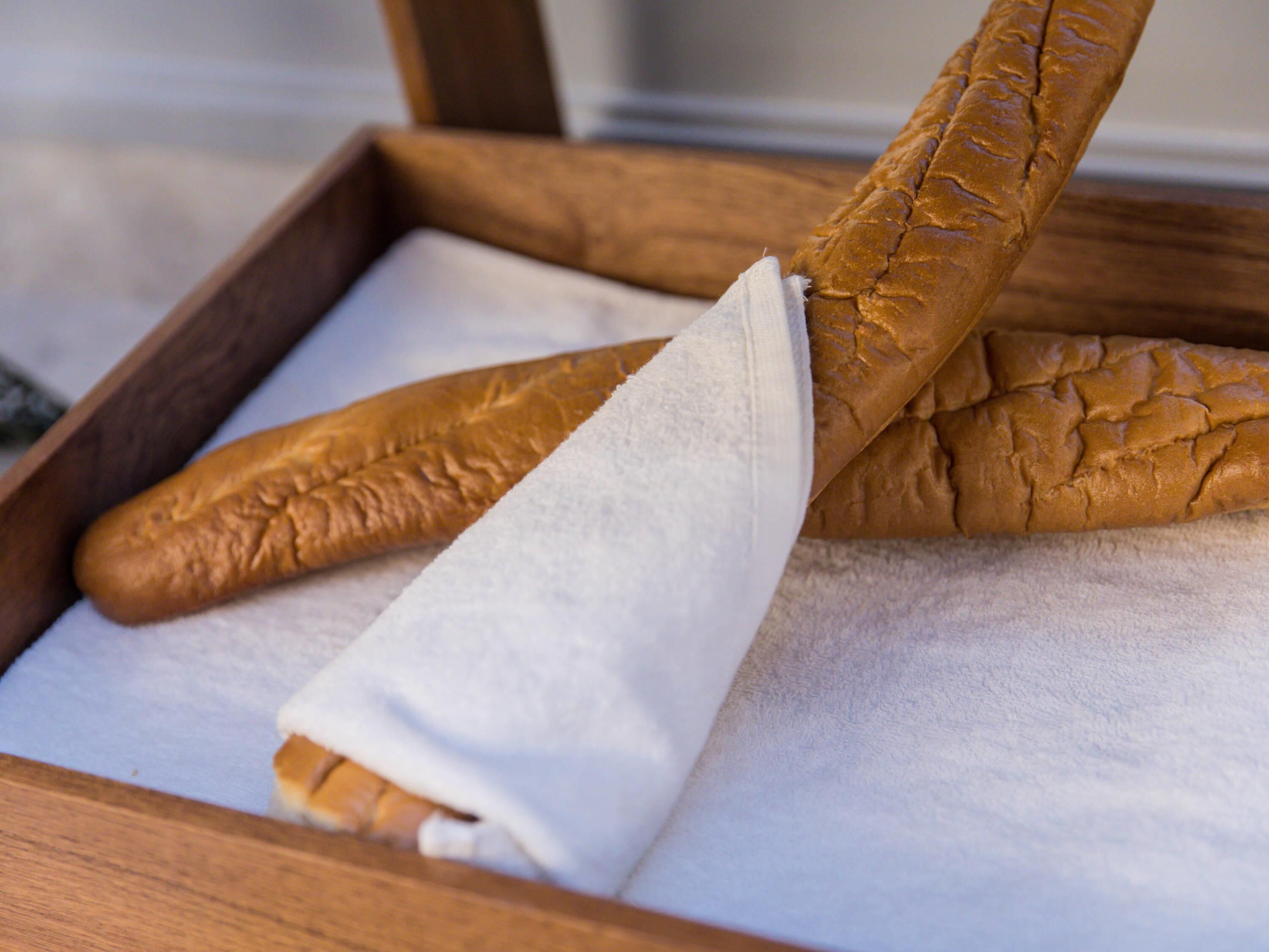 Un plateau en bois contenant deux baguettes emballées dans du papier blanc.