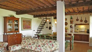Ein gemütliches Wohnzimmer mit einer blumengedeckten Couch, einem Holzschrank und einer Treppe, die in einen oberen Bereich führt.