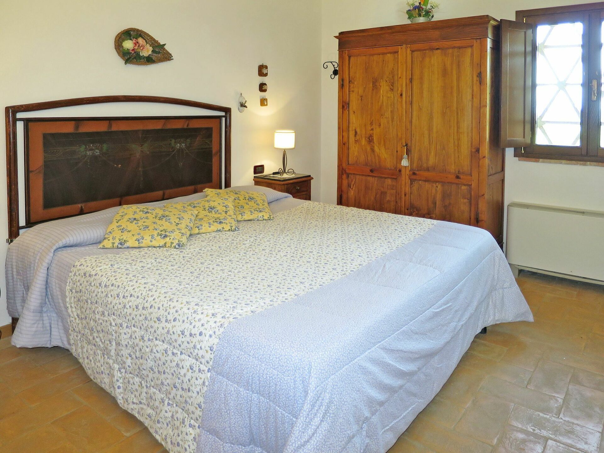 Une chambre avec un grand lit, une armoire en bois et une fenêtre donnant sur un beau paysage.