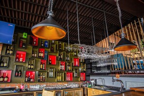 A bar area with shelves of liquor bottles, a bar counter, and hanging light fixtures.
