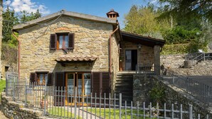 Una casa in pietra con un cancello in metallo, una scala e un piccolo giardino.