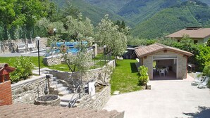 Un edificio in pietra con un portico, circondato da un muro di pietra e un piccolo giardino.
