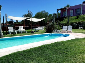 A swimming pool with white lounge chairs and a canopy. - Cabañas & Apart Yki Shamuaika (Capilla del Monte)