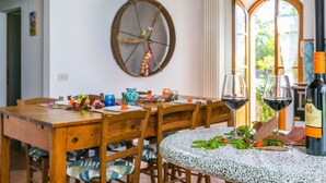 Un coin repas avec une table en bois, des chaises et une petite table ronde sur laquelle se trouvent une bouteille de vin et des verres.