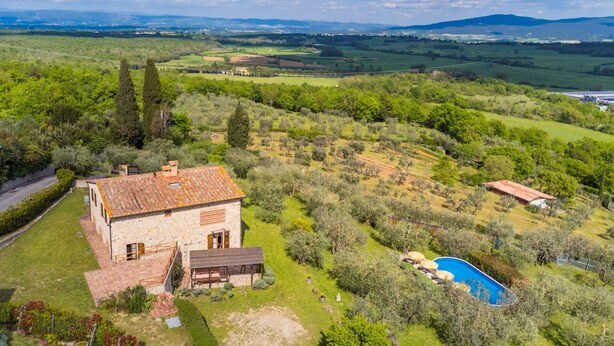 Une maison en pierre avec un toit en tuiles, une piscine et un jardin bien entretenu.