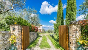Un chemin de pierres mène à un bâtiment rustique doté de portails en bois et de vases de fleurs.