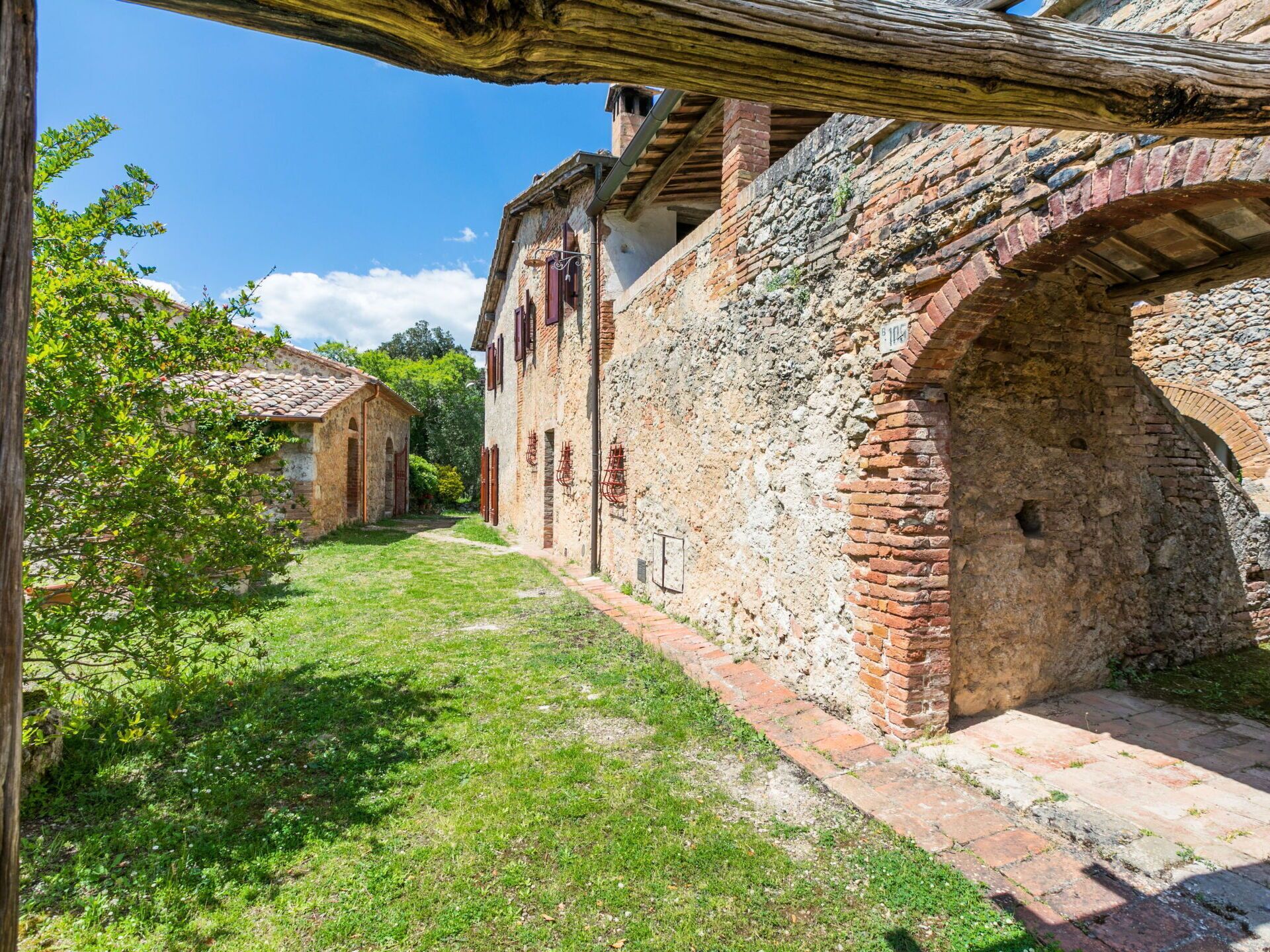 Un vieux bâtiment en pierre, doté d’une cour étroite, de portes en arc de cercle et d’une poutre en bois rustique au-dessus de l’entrée.