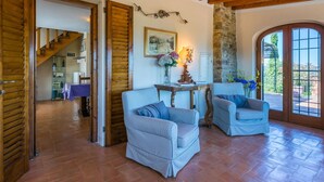 A spacious living area with two checkered armchairs, a wooden ceiling, a stone wall, and a view through a large arched doorway. - Wonderful private villa for 5 guests with WIFI, private pool, TV, terrace and panoramic view (Impruneta)