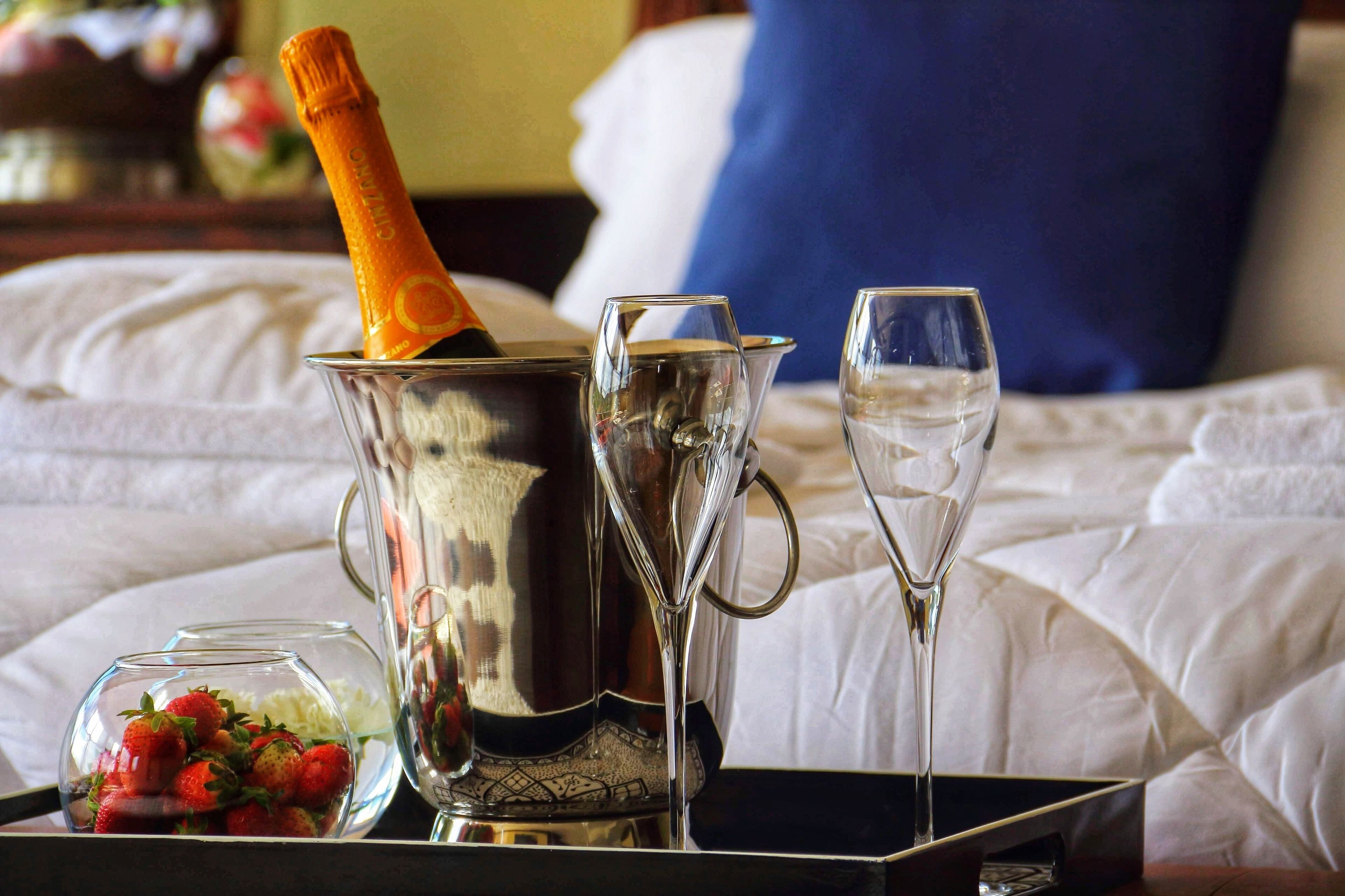 Un vassoio con una bottiglia di champagne, una brocca e un bicchiere d'acqua su un letto.