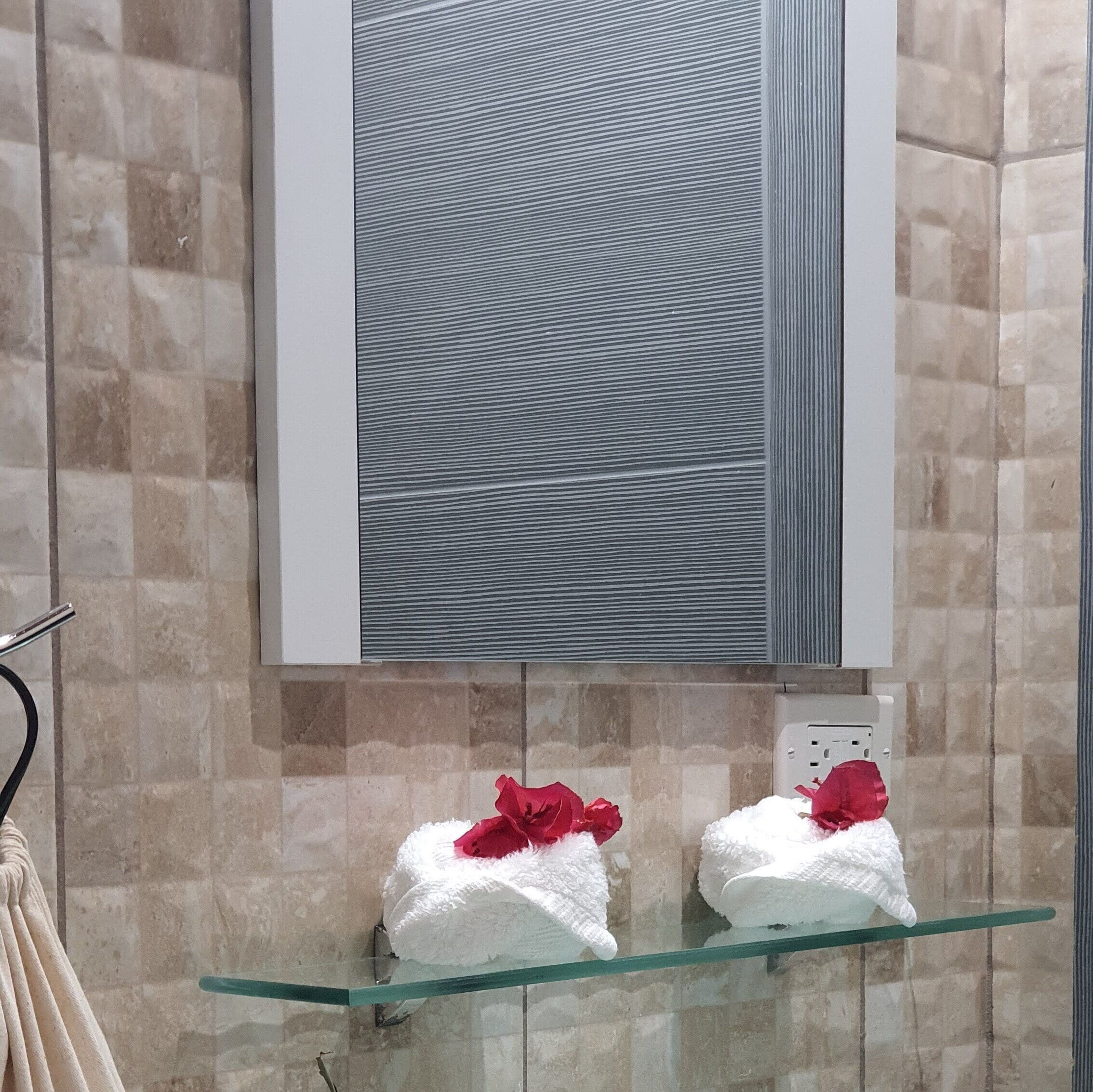 Un baño con repisas de vidrio que sostienen dos toallas, un espejo y una pared con textura.
