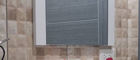 Un baño con repisas de vidrio que sostienen dos toallas, un espejo y una pared con textura.