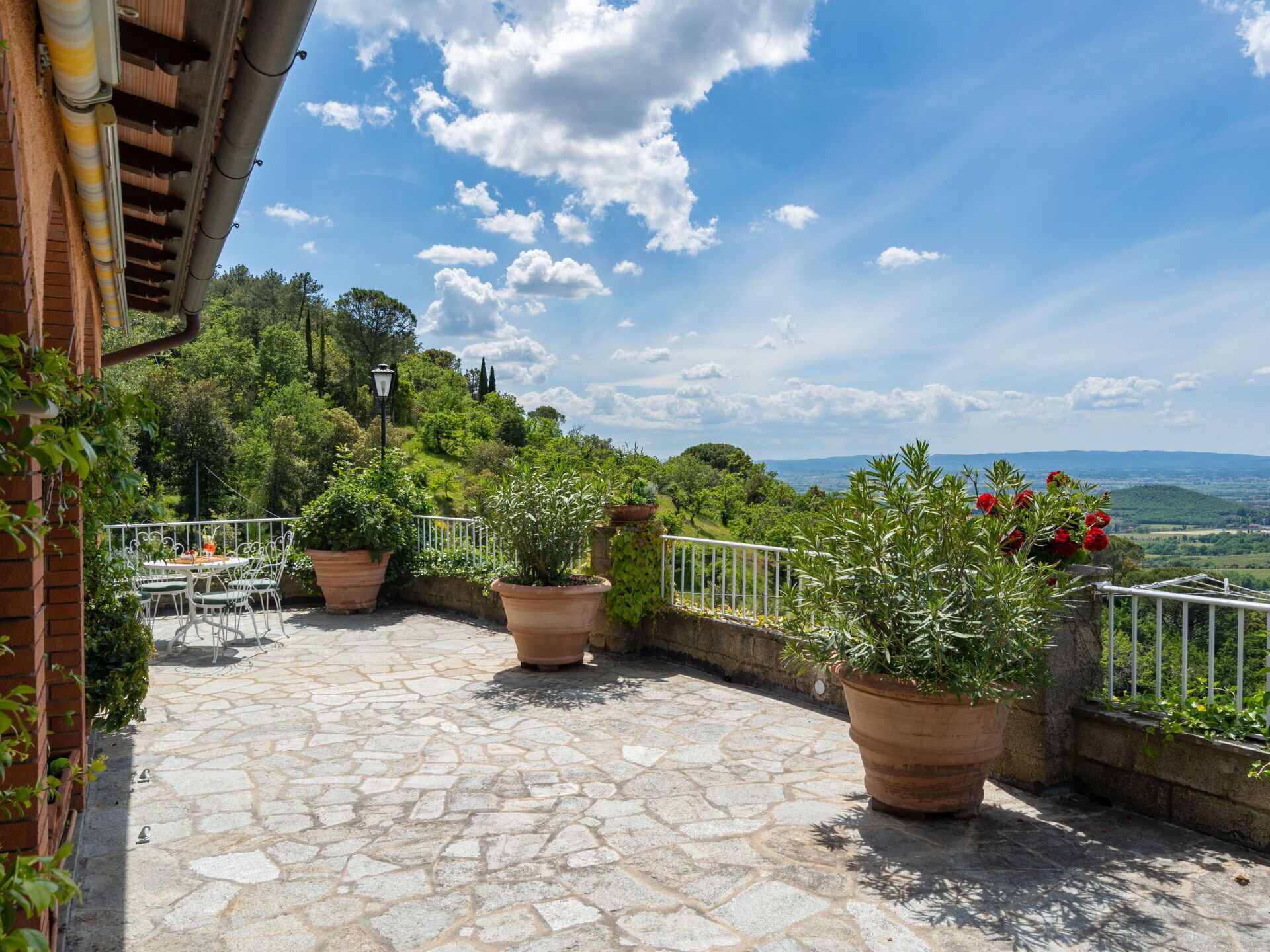 Un patio empedrado con mesas al aire libre y plantas en macetas.