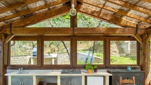 Una cucina rustica con parete in pietra, travi in legno e un'ampia finestra vista giardino.