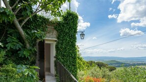 Un vialetto in pietra conduce a una porta circondata da vegetazione lussureggiante e una ringhiera in metallo.