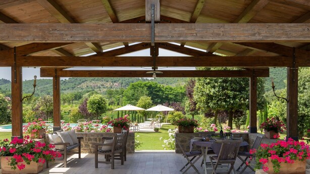 An outdoor patio with stone flooring, wooden furniture, and potted flowers. - Beautiful private villa for 7 guests with private pool, WIFI, TV, patio and pets allowed (Castiglion Fiorentino)