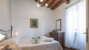 Een slaapkamer met een bed, nachtkastjes, een dressoir, een spiegel en een schilderij aan de muur.