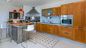 Eine moderne Küche mit Holzschränken, Edelstahlgeräten und einer Bar mit Hockern.