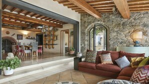 A cozy living area with a stone wall, wooden beams, a red sofa, and a yin-yang rug. - Beautiful private villa for 9 guests with WIFI, A/C, private pool, TV, terrace and pets allowed (Buti)