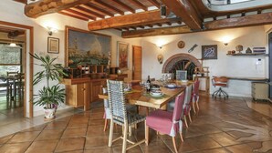 A spacious dining area with a wooden table, chairs, and a brick fireplace. - Beautiful private villa for 9 guests with WIFI, A/C, private pool, TV, terrace and pets allowed (Buti)