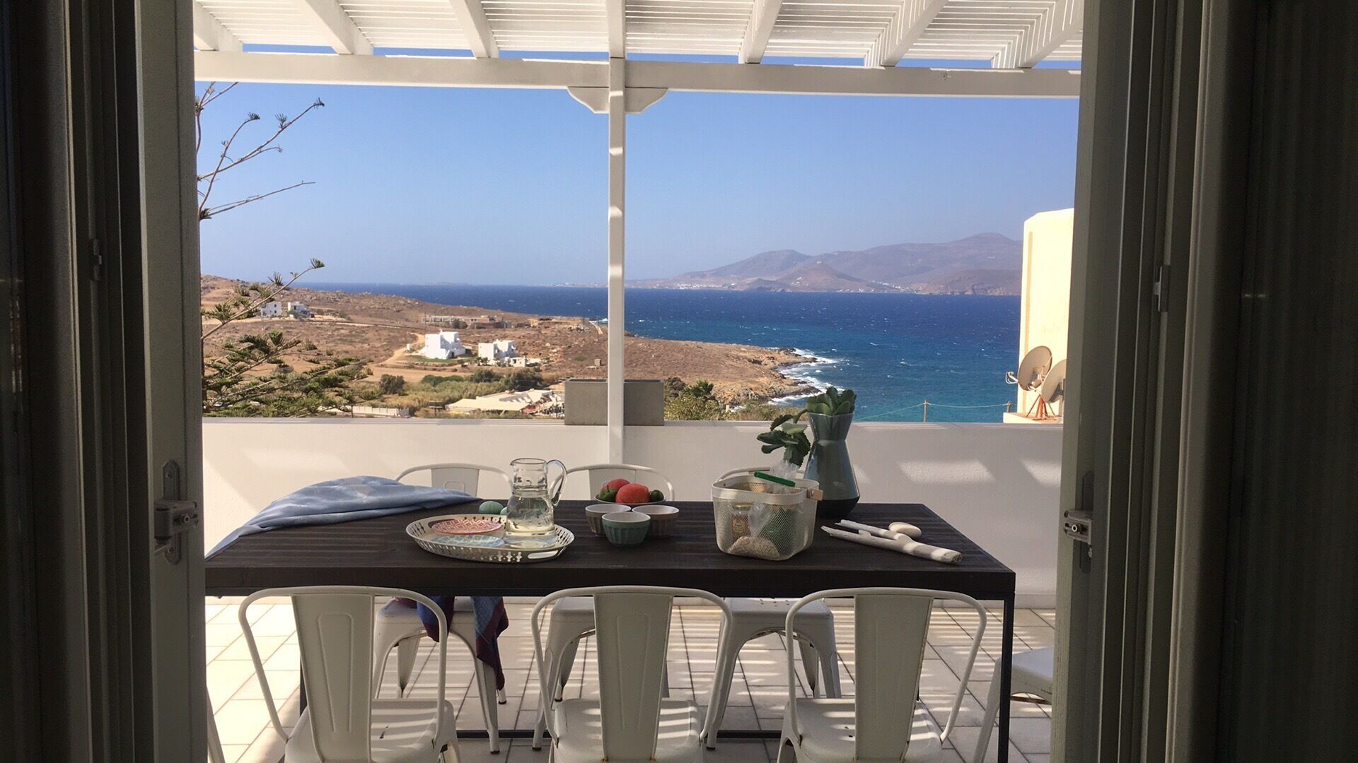 A table set for two with a view of the sea and mountains.