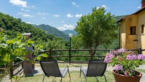Two rocking chairs facing a scenic mountain view, a wooden fence, and a potted plant with pink flowers. - Stunning private villa for 10 guests with WIFI, private pool, TV, patio and pets allowed (Londa)