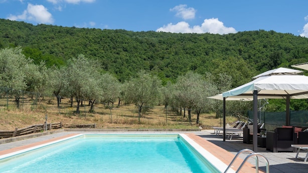 A rectangular swimming pool with a clear blue water, surrounded by a tiled deck. There is a covered seating area with outdoor furniture and umbrellas. - Stunning private villa for 10 guests with WIFI, private pool, TV, patio and pets allowed (Londa)