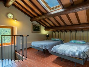 Un dormitorio con dos camas, un tragaluz, un cuadro y una ventana con vistas al verdor.
