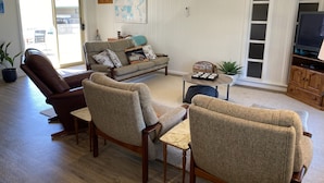 A living room with a sofa, two armchairs, a coffee table, and a television. - The 19th Green - Located near the golf course! Pet Friendly - Outside Only (Robe)