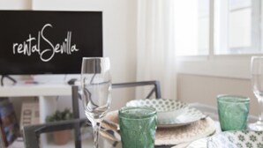Et spisebord med tallerkener, glas og en tavle med teksten 'rental Sevilla'.
