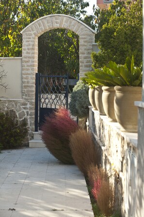 Stroll through the beautifully landscaped entrance, flanked by lush greenery and elegant planters.