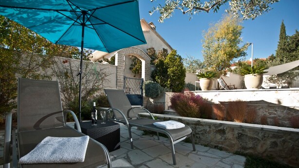 Un espace patio comprenant deux chaises longues, une table et un parasol bleu.