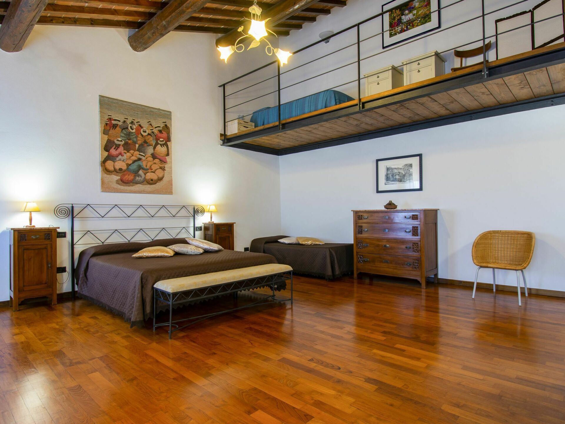 A bedroom with a bed, bedside tables, a dresser, a chair, and a loft area with a railing.