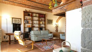 Una sala de estar acogedora con una chimenea de ladrillo, una estantería llena de libros, un sofá azul claro y una alfombra estampada.