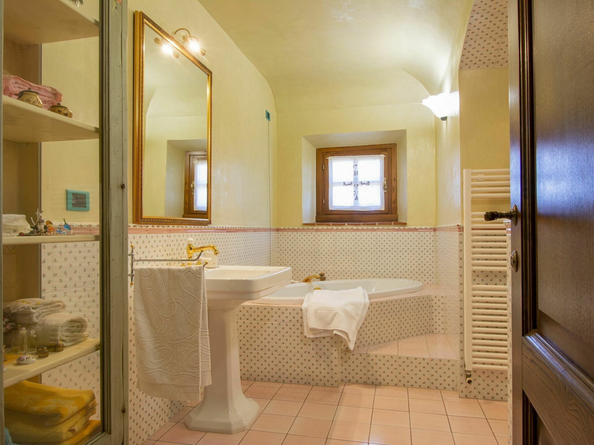 A bathroom with a large mirror, a sink, a bathtub, and a window.