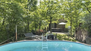 A swimming pool surrounded by trees, with lounge chairs and a stone building in the background. - Stunning private villa for 4 guests with private pool, TV, patio and pets allowed (Camucia-monsigliolo)
