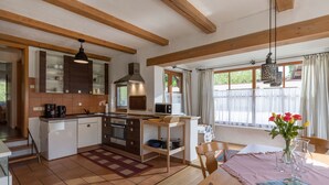 Eine gemütliche Küche mit Holzbalken, einem Essbereich mit Tisch und Stühlen sowie einem Fenster mit Vorhängen.