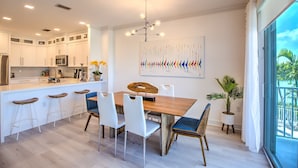 A modern kitchen with white cabinets, a wooden dining table, and bar stools. - Walk to Sombrero Beach! (Marathon)