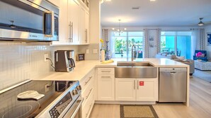 A modern kitchen with white cabinetry, a Bosch microwave, a coffee maker, and a dishwasher. - Walk to Sombrero Beach! (Marathon)