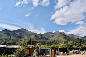 A rural village with traditional houses, a small river, and mountains in the background.