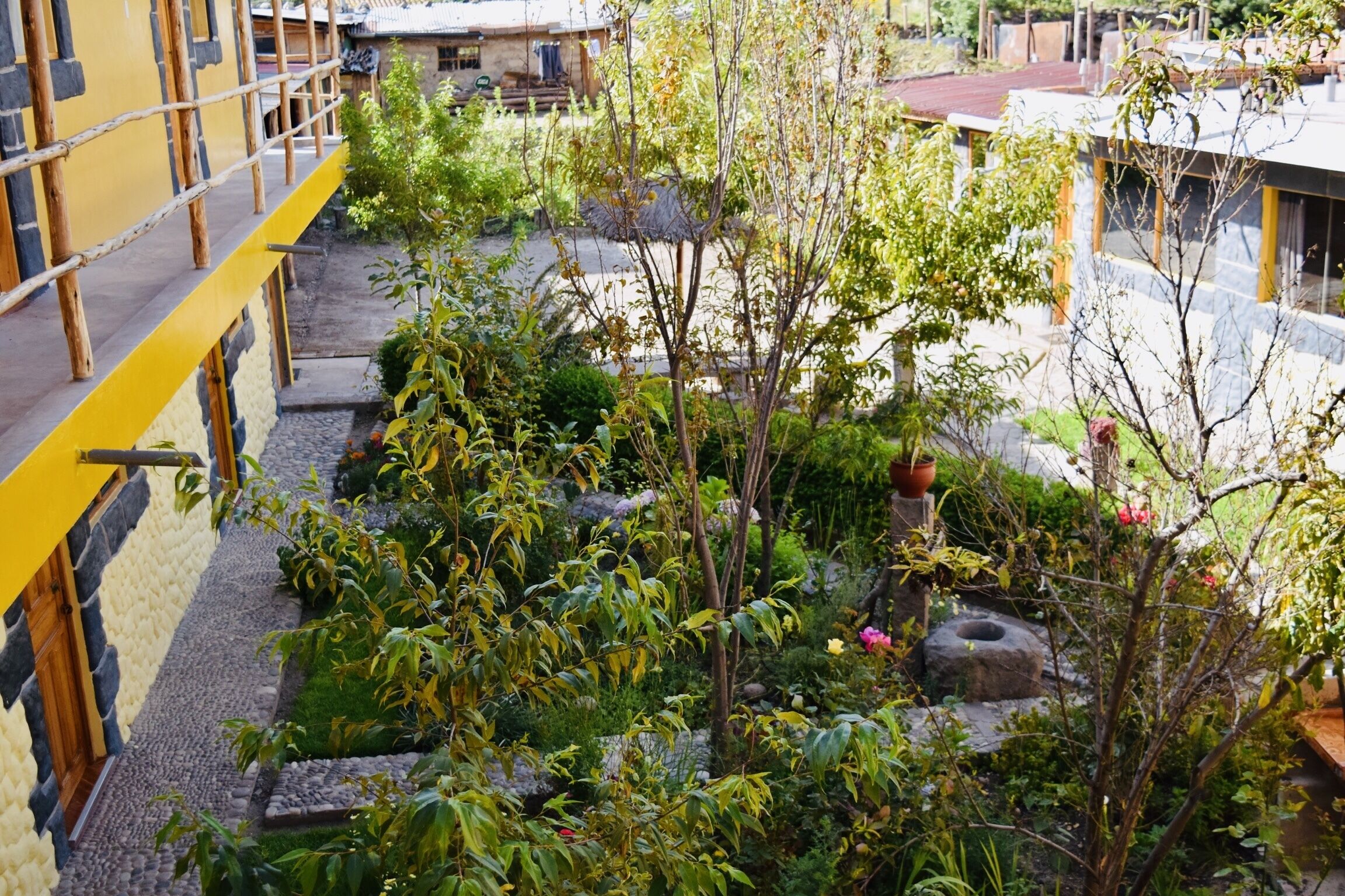 A courtyard with a yellow railing, stone pathway, and various plants.