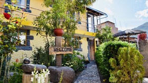 Un edificio con un letrero de 'WELCOME', un sendero de piedra y abundante vegetación.