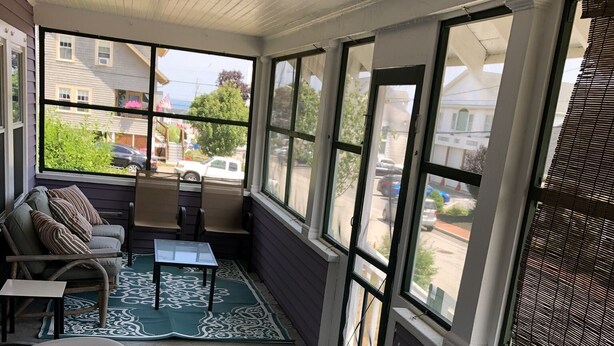 Una sala de estar con ventanales, una mesa grande con sillas, un sofá y vistas a la calle.