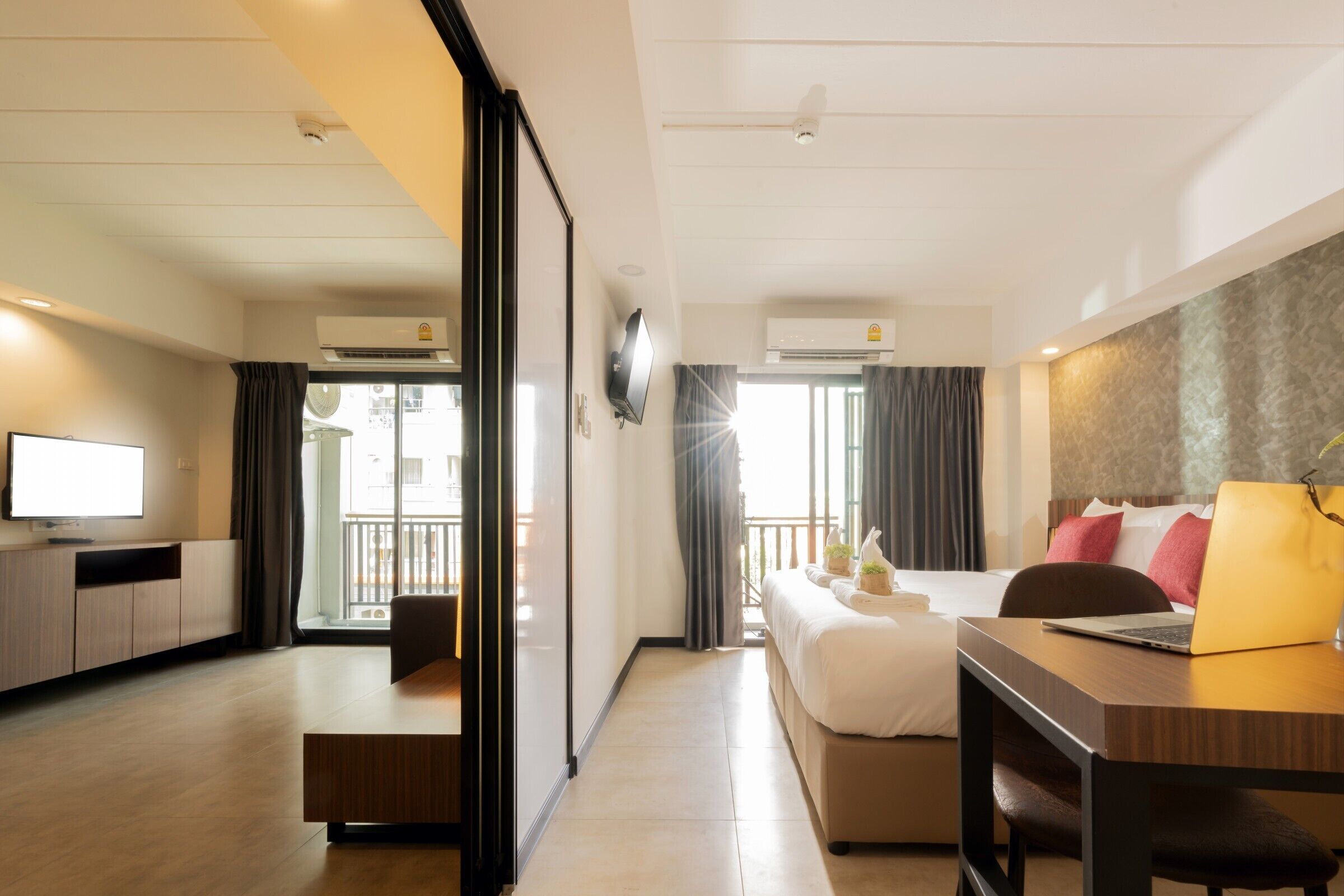 A modern hotel room with a bed, desk, and TV.