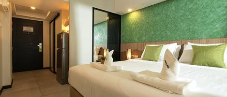 Quarto de hotel com uma cama grande, parede verde com textura e um espelho.