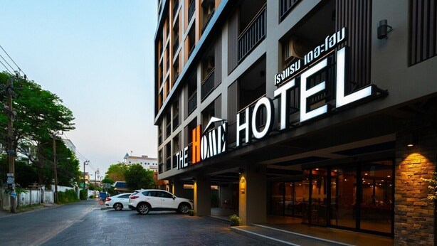 A hotel with a modern facade, multiple floors, and a prominent sign reading "The Home Hotel". - The Home Hotel (Bangkok)