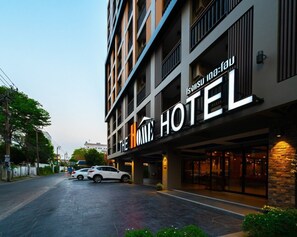 A hotel with a modern facade, multiple floors, and a prominent sign reading "The Home Hotel". - The Home Hotel (Bangkok)