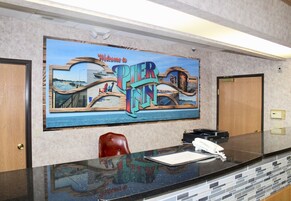 Una recepción con un mural que dice "Welcome to Pier 39", una silla roja, un teléfono y una libreta.